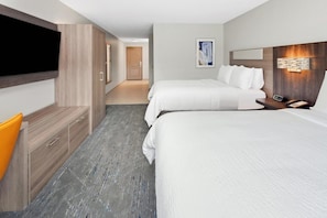 A hotel room with a flat-screen TV, two beds, a desk with a chair, and a hallway leading to another room. - Port Wisconsin Inn and Suites (Port Washington)