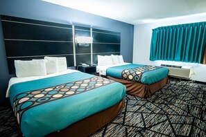 A hotel room with two beds, a large headboard, a window with curtains, and a patterned carpet. - Asteria Inn and Suites (New Richmond)