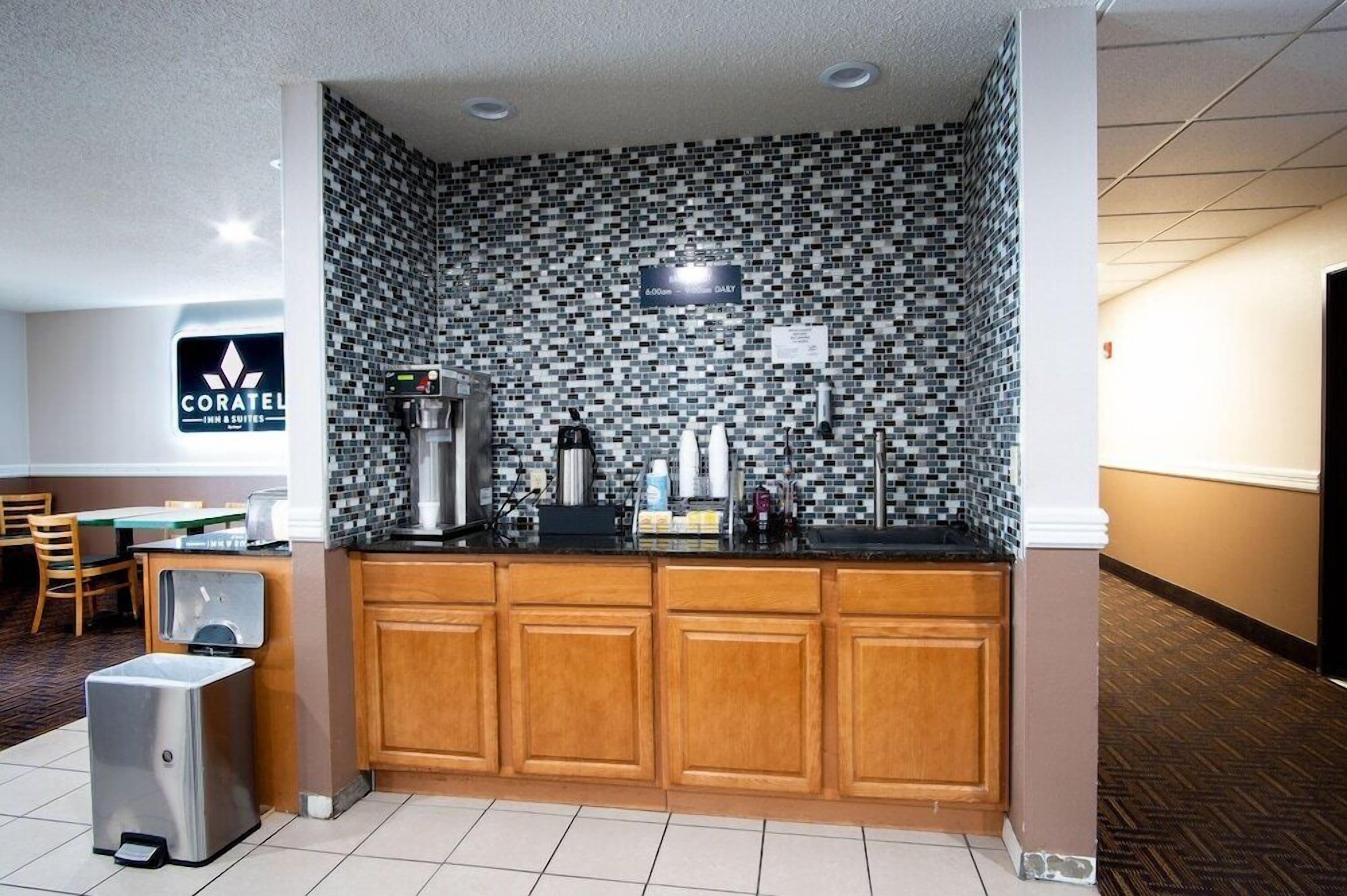 A hotel kitchen with a black and white mosaic backsplash, wooden cabinets, and a coffee machine.