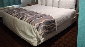Ein Hotelzimmer mit Bett, Kopfteil, Nachttisch, einem Fenster mit Vorhängen und einem Wandbild.