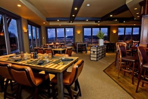 A restaurant with multiple tables and chairs, large windows with a view, and a central plant. - The Inns Of Geneva National (Lake Geneva)