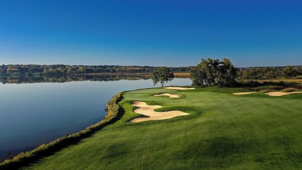 A golf course with sand bunkers, a lake, and trees. - The Inns Of Geneva National (Lake Geneva)