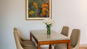 A dining area with a table and four chairs, a vase with flowers, and a framed painting on the wall. - The Ingleside Hotel (Pewaukee)