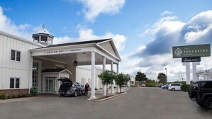 A hotel entrance with a covered registration area, a signboard, and a parking lot. - The Ingleside Hotel (Pewaukee)