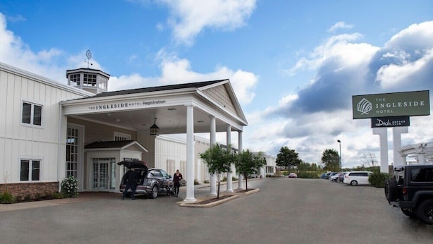 A hotel entrance with a covered registration area, a signboard, and a parking lot. - The Ingleside Hotel (Pewaukee)