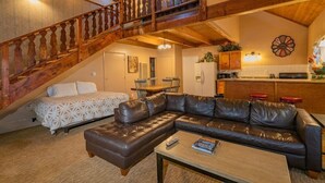 Una sala de estar acogedora con un sofá de cuero, una mesa de centro y una escalera que sube a un nivel superior.