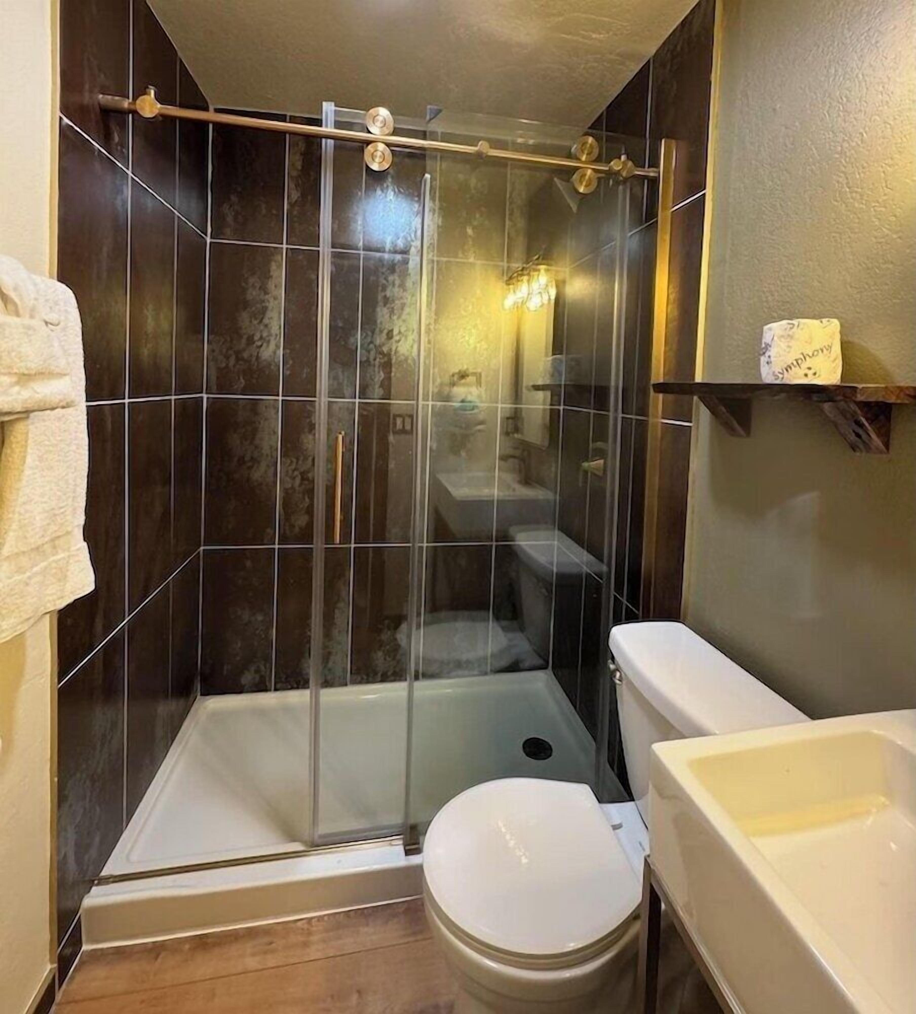 Une douche avec une porte en verre, des toilettes et un lavabo.
