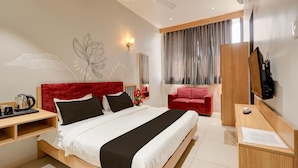 Een moderne hotelkamer met een groot bed, een bureau, een rode stoel, een televisie en een plafondventilator.