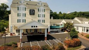 A two-story hotel with a central entrance, a parking lot, and a green roof. - D. Hotel and Suites (Holyoke)