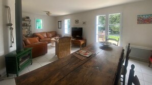 Uma sala de estar com mesa de jantar de madeira, sofá de couro e lareira a lenha verde.
