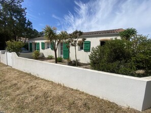 Ein Gebäude mit weißer Fassade, grünen Fensterläden und einem weißen Zaun.
