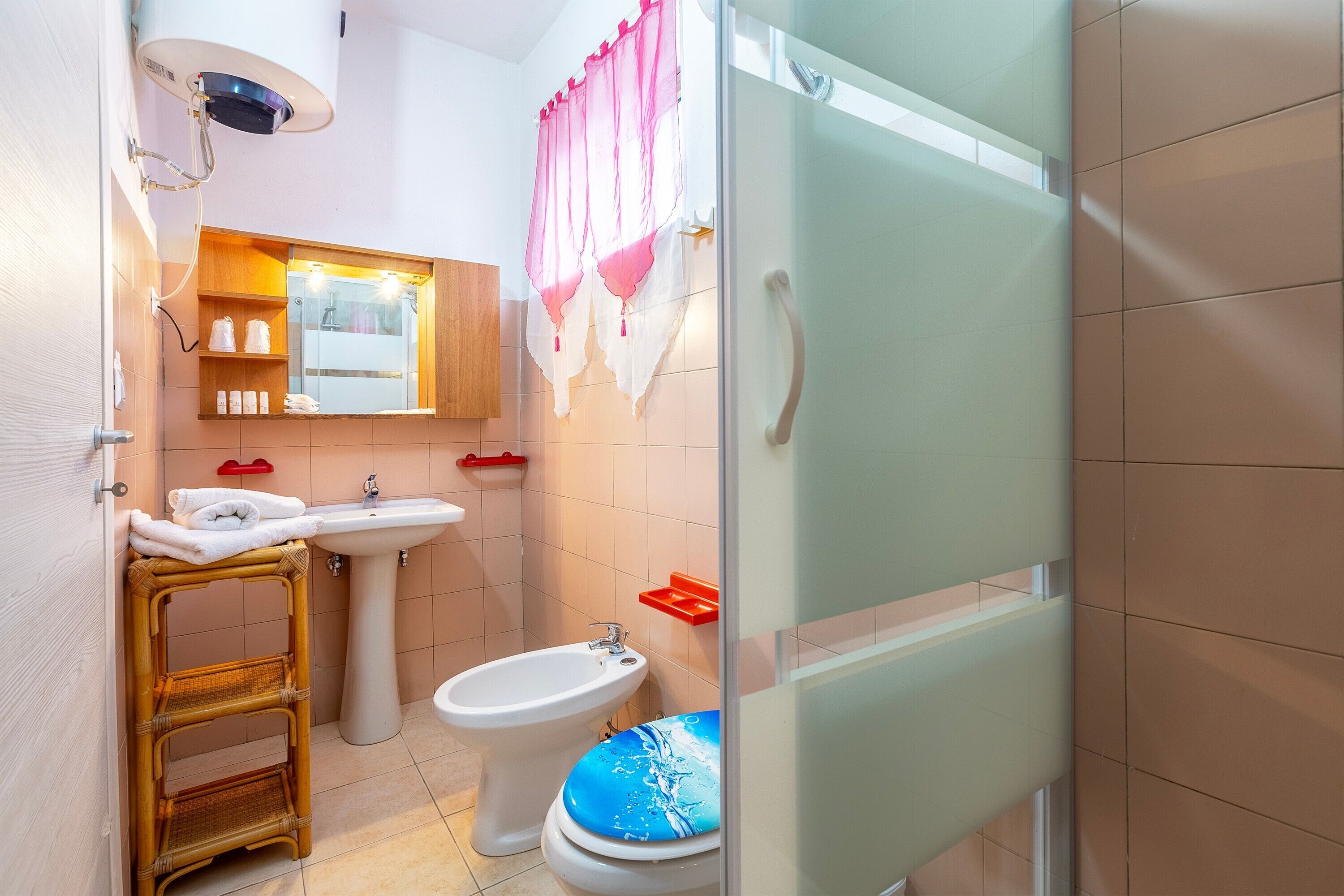 A bathroom with a bidet, a sink, a mirror, a towel rack, and a glass shower enclosure.