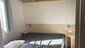 Ein kleines Schlafzimmer mit Bett, Schreibtisch und integrierten Stauraumschränken.