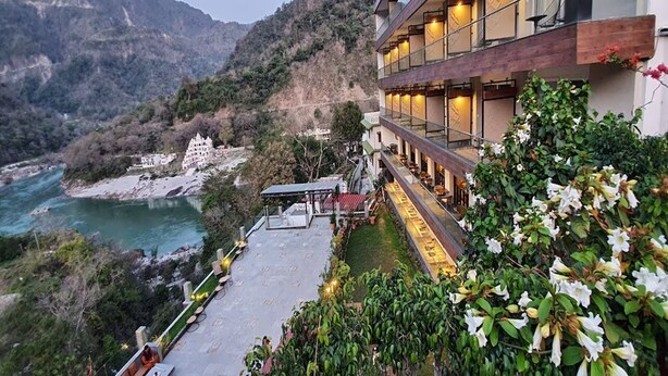 A hotel with a terrace overlooking a river and mountains, featuring a modern design with multiple balconies and a garden area. - Antalya By Divine Ganga Cottage (Narendranagar)
