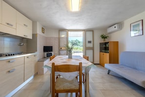 Une cuisine moderne avec une table à manger, des chaises, un canapé et une vue sur l’extérieur grâce à une porte vitrée.