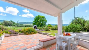 A covered patio with a tiled floor, white chairs, a table with a bottle and glasses, and a view of the countryside. - Apartment 'Villa Singola 3' with Mountain View, Wi-Fi and Air Conditioning (La Muddizza)