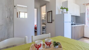 A modern kitchen with white cabinets, a built-in oven, and a small dining area with a green tablecloth. - Apartment 'Villa Singola 2 Sea View' with Private Terrace and Air Conditioning (La Muddizza)