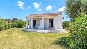 A white building with a red-tiled roof, a covered patio with chairs, and a well-maintained lawn. - Apartment 'Villa Singola 2 Sea View' with Private Terrace and Air Conditioning (La Muddizza)