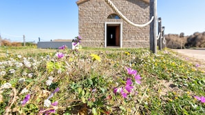 A stone church with a rope barrier, surrounded by wildflowers. - Apartment 'Villa Singola 2 Sea View' with Private Terrace and Air Conditioning (La Muddizza)