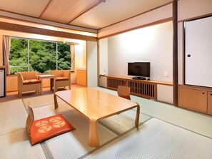 Une pièce de style japonais traditionnel, avec un sol recouvert de tatamis, une table basse et un téléviseur posé sur un meuble en bois.