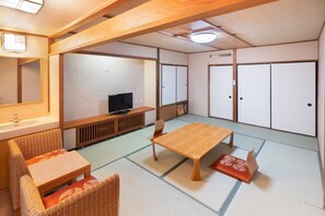 Una tradizionale stanza giapponese con pavimento in tatami, un tavolino in legno, una televisione e un futon.