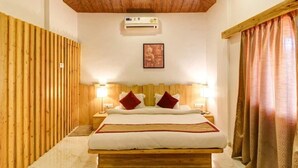 A bedroom with a wooden ceiling, a bed with white bedding, two bedside lamps, and a wall-mounted air conditioner. - Maooli Home Stay (Mahabaleshwar)