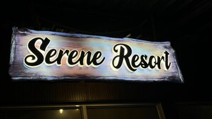 A sign for Serene Resort with a rustic wooden background and illuminated lettering. - Maooli Home Stay (Mahabaleshwar)