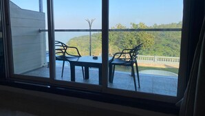 A balcony with a table and chairs, overlooking a lush green landscape. - Maooli Home Stay (Mahabaleshwar)