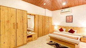 A bedroom with a large wooden wardrobe, a bed with red pillows, and an air conditioning unit on the wall. - Maooli Home Stay (Mahabaleshwar)