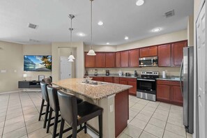A modern kitchen with granite countertops, stainless steel appliances, and wooden cabinets. - 4 Bed Close to Disney Private Pool (Kissimmee)