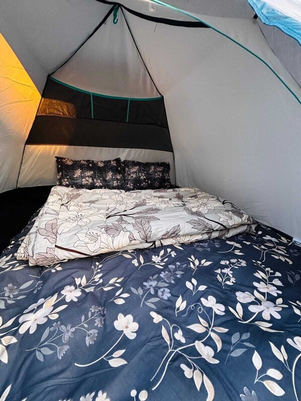 A tent with a bed inside, featuring a floral bedspread and pillows.