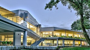 A modern building with a glass facade, outdoor seating, and a staircase leading to an upper level. - Forest Beach Hotel (Kiten)