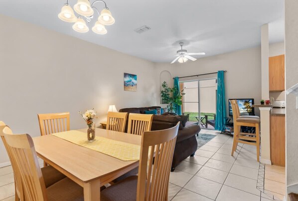A dining area with a wooden table and chairs, a ceiling fan, and a view of the outdoors. - Tranquil Townhouse 3 bed Lazy River Resort (Davenport)