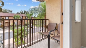 A balcony with a view of a residential area, a chair, and a door. - Tranquil Townhouse 3 bed Lazy River Resort (Davenport)