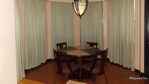 Een eetkamer met een ronde tafel, vier stoelen en een kroonluchter.