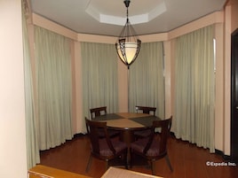 A dining room with a round table, four chairs, and a chandelier.