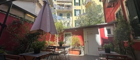An outdoor patio area with tables and chairs, surrounded by buildings.