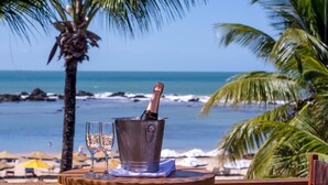 Een tafel aan het strand met een champagnefles en glazen, met uitzicht op de oceaan.