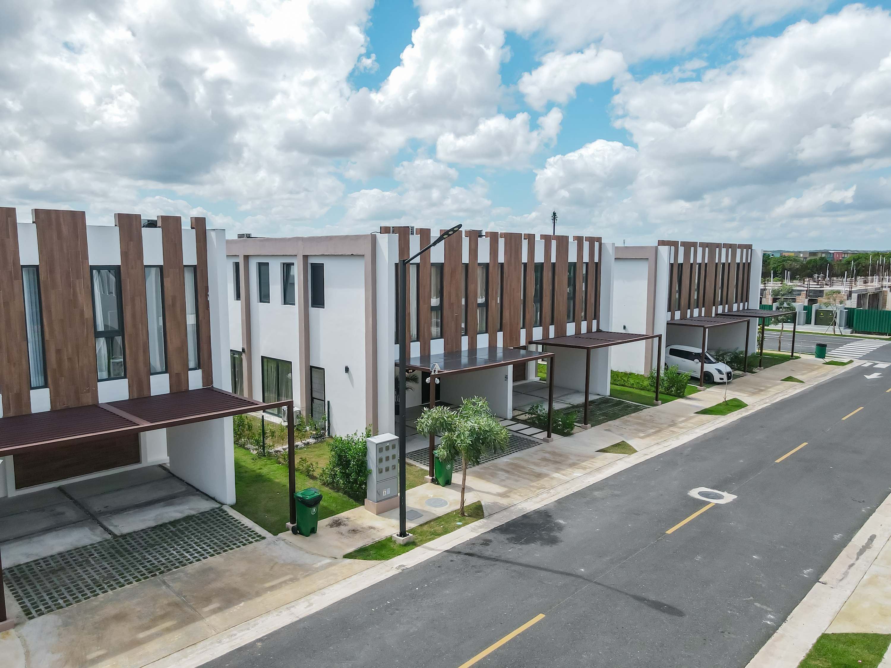 A modern residential building with a clean design, a covered outdoor seating area, and a street view.
