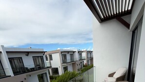 Ein Balkon mit Korbstuhl, einem kleinen Pool und Blick auf moderne Gebäude.