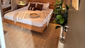 A bedroom with a wooden bed, a hanging light fixture, woven wall decor, and a potted plant. - NOK Modern 3BR Villa With Patio by Vistacana (Punta Cana)