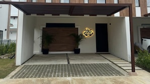 A modern two-story house with a flat roof, a wooden facade, and a black door. - NOK Modern 3BR Villa With Patio by Vistacana (Punta Cana)