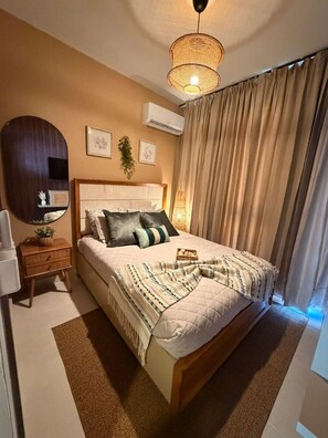 A bedroom with a large bed, a bedside table, a mirror, and a hanging plant. - NOK Modern 3BR Villa With Patio by Vistacana (Punta Cana)