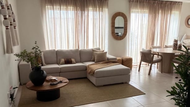 A modern living room with a sectional sofa, a coffee table, and a dining area with a table and chairs. - NOK Modern 3BR Villa With Patio by Vistacana (Punta Cana)