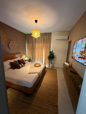 A neatly arranged bedroom with a bed, bedside tables, a TV, and a potted plant. - NOK Modern 3BR Villa With Patio by Vistacana (Punta Cana)