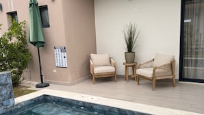 A swimming pool with two lounge chairs and a potted plant. - NOK Modern 3BR Villa With Patio by Vistacana (Punta Cana)