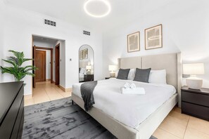 A modern hotel room with a large bed, bedside tables, a mirror, and a potted plant. - Stayshort - 2 Bed in Downtown That Sleeps 6 With Burj Khalifa View (Dubai)