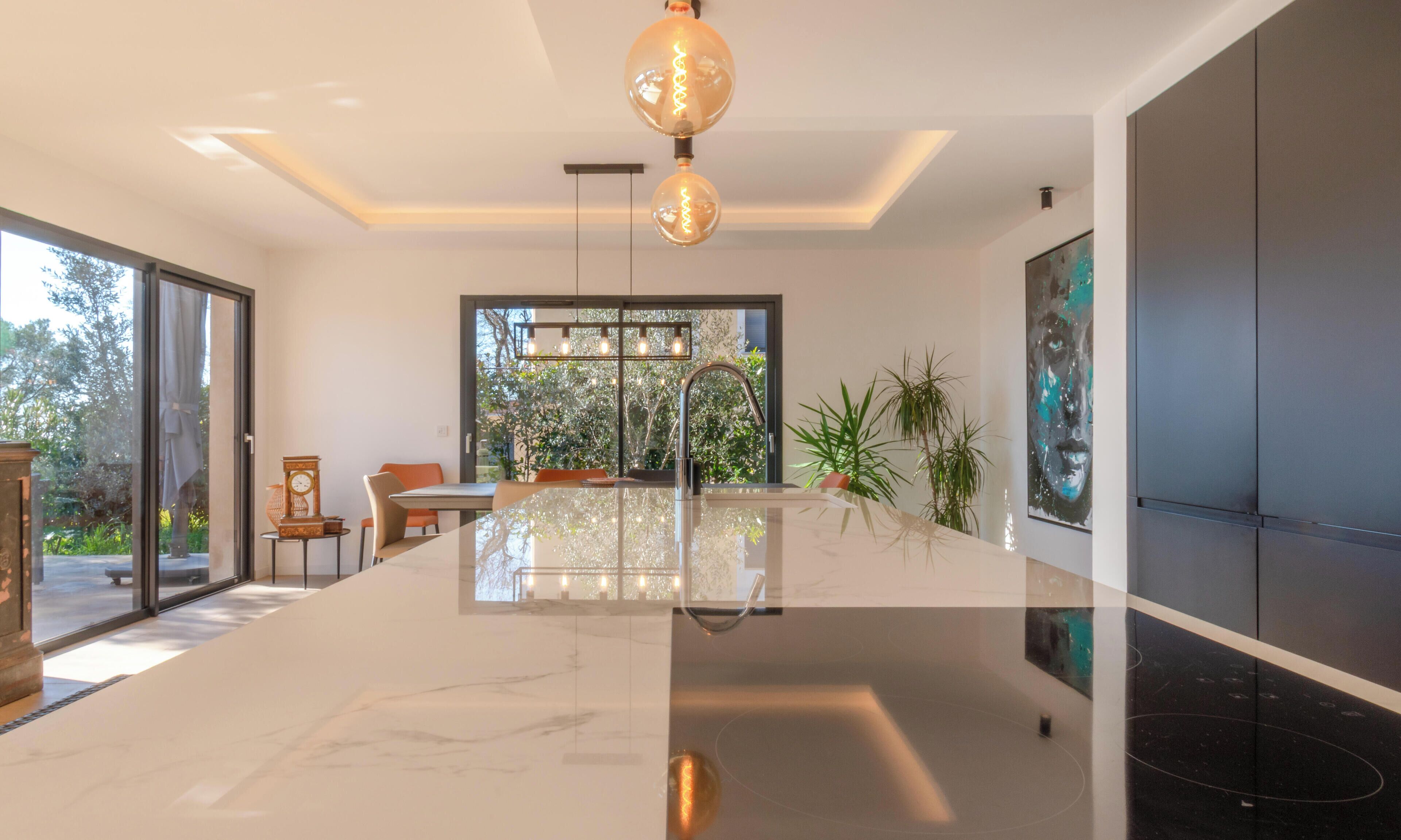 A modern kitchen with a marble countertop, a stainless steel sink, and pendant lighting.
