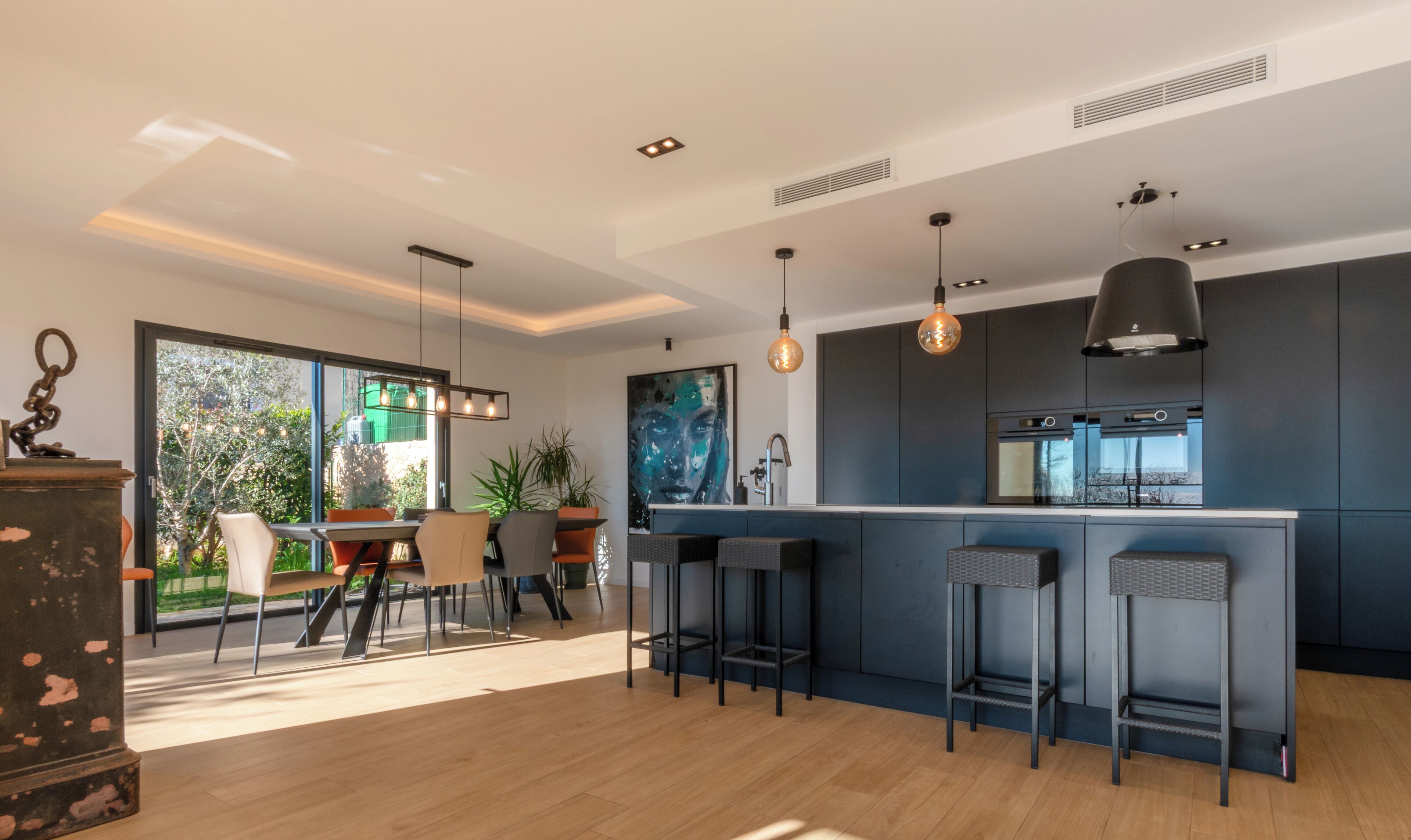 A modern kitchen with a bar area, large windows, and a dining space with a view.