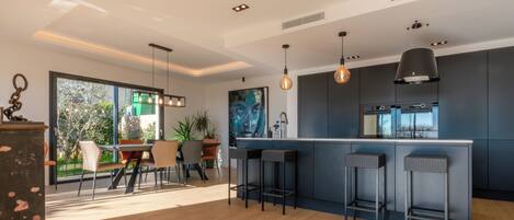 A modern kitchen with a bar area, large windows, and a dining space with a view.